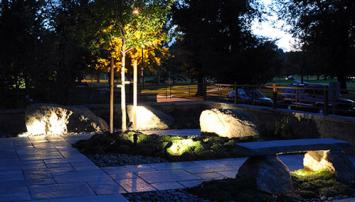Landscape lighting with rocks, walkway, and trees